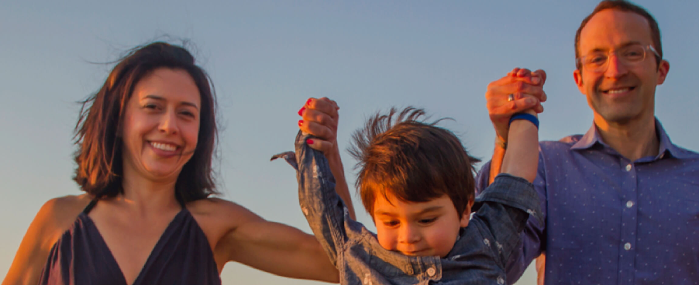 Young boy with having fun with new parents on an evening walk.